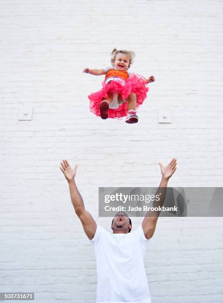 father tossing baby girl into air - tossing baby in air stock pictures, royalty-free photos & images