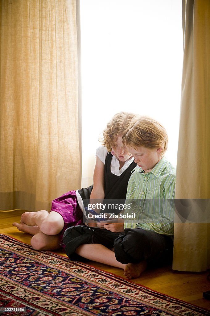 Brother & sister with small computer game player