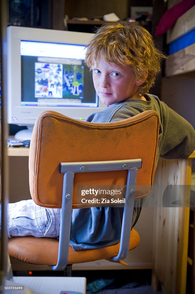 Boy in his bedroom with his computer