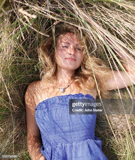 young woman lying amongst tall grasses - tall blonde women stock pictures, royalty-free photos & images