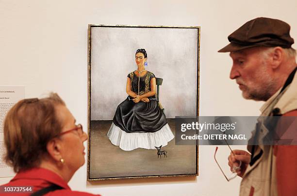 Visitors look at a painting by Mexican artist Frida Kahlo titled "self-portrait with Itzcuintli-dog" during the opening of a show of her works on...