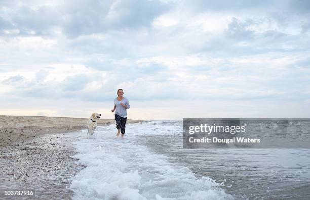 woman with dog running along beach. - dougal waters 個照片及圖片檔