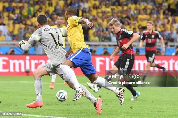 Germany_s Toni Kroos takes a shot on goal against Brazil's goal keeper Julio Cesar and Fernandinho during the FIFA World Cup 2014 semi-final match...