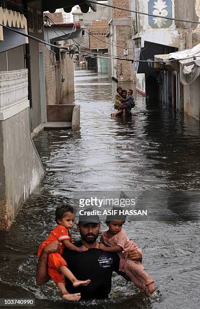 Pakistani volunteers rescue children as they wade through floodwater in Sujawal in southern Sindh province on August 30, 2010. A torrent of water...