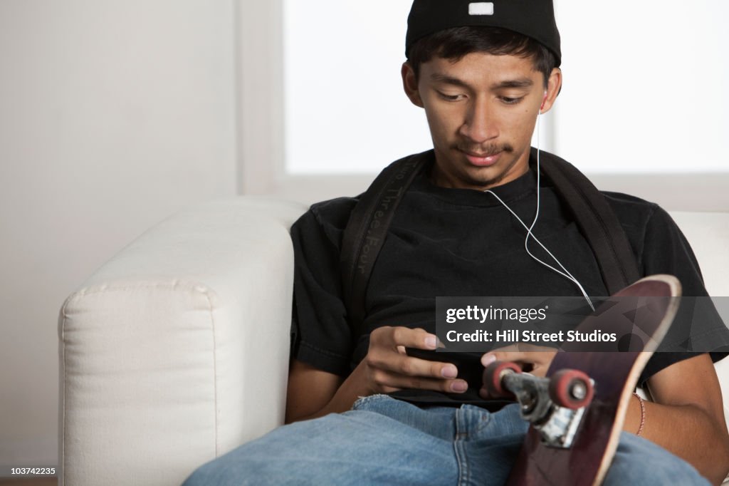 Hispanic man text messaging on cell phone