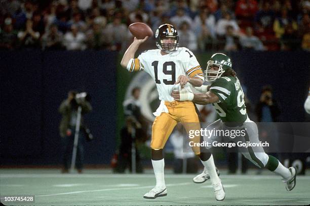 Quarterback David Woodley of the Pittsburgh Steelers passes as he is tackled by defensive lineman Mark Gastineau of the New York Jets at Giants...