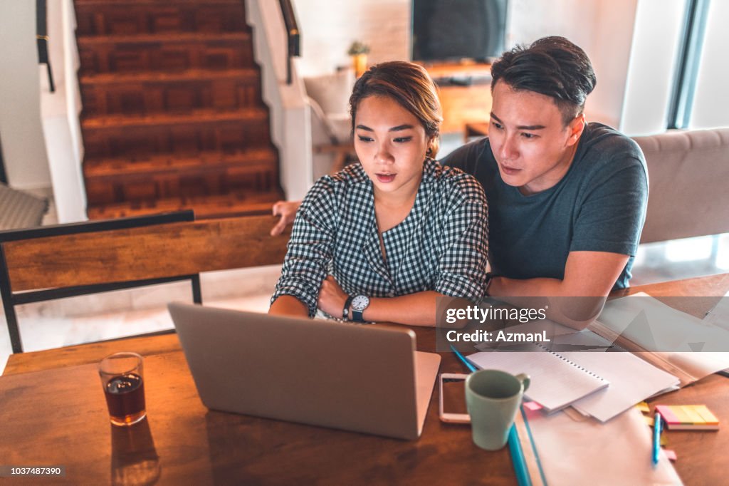 Serious couple using laptop while sitting at home