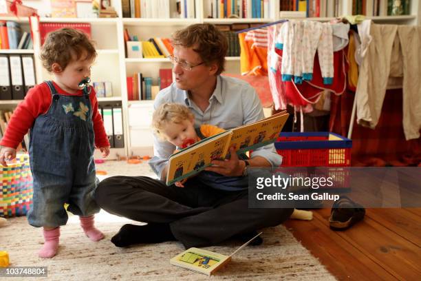 Oliver H. A married federal employee on 6-month paternity leave, reads to his twin 14-month-old daughters Alma and Lotte at his home on August 31,...