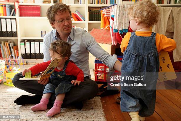 Oliver H. A married federal employee on 6-month paternity leave, reads to his twin 14-month-old daughters Alma and Lotte at his home on August 31,...