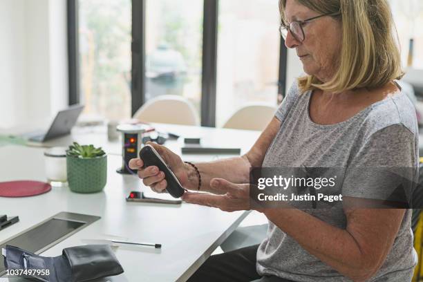 senior woman checking blood sugar levels - diabetes technology stock pictures, royalty-free photos & images