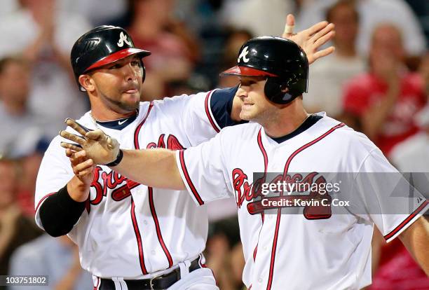 Alex Gonzalez of the Atlanta Braves congratulates David Ross after Ross' grand slam in the fifth inning against the New York Mets at Turner Field on...