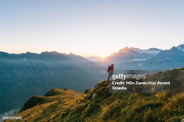 female hiker climbs mountain ridge, high above valley - schweizer alpen stock-fotos und bilder