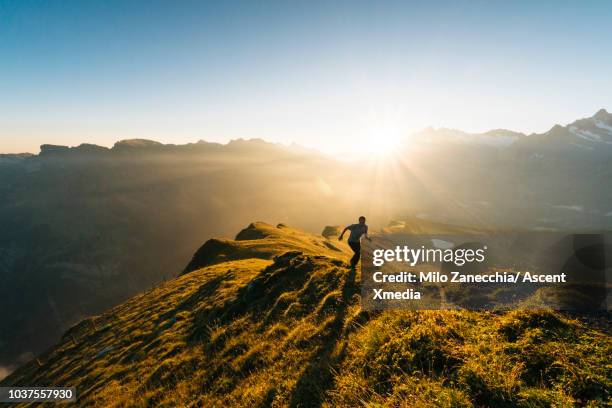 male trail runner ascends mountain ridge, high above valley - runner sunrise stock pictures, royalty-free photos & images
