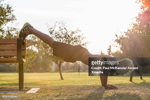 muscular young man performs exercises in urban park - ew stock pictures, royalty-free photos & images
