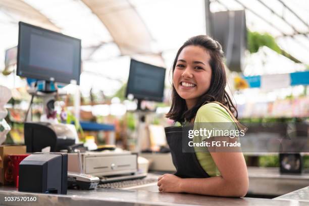 portrait of confident owner leaning on checkout counter at flower shop - checkout stock pictures, royalty-free photos & images