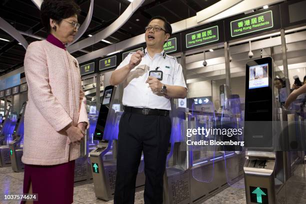 Carrie Lam, Hong Kong's chief executive, listens in front of automated immigration clearance machines for departing passengers during a tour in the...