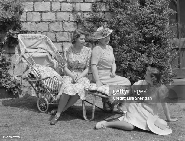 Princess Elizabeth and Queen Elizabeth, The Queen Mother seated on a sun lounger with Princess Margaret seated on the grass in the garden at Windsor...