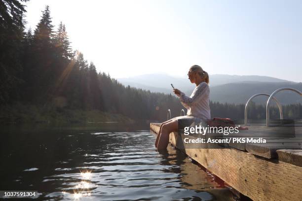 woman relaxes on dock above mountain lake - locs hairstyle stockfoto's en -beelden