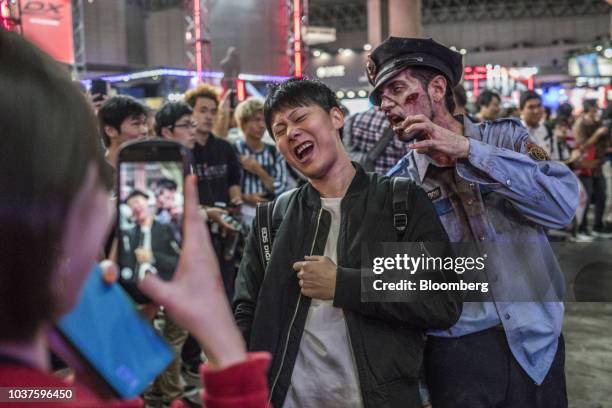 An attendee poses for a photograph with an actor dressed as a zombie during the Tokyo Game Show in Chiba, Japan, on Saturday, Sept. 22, 2018. The...