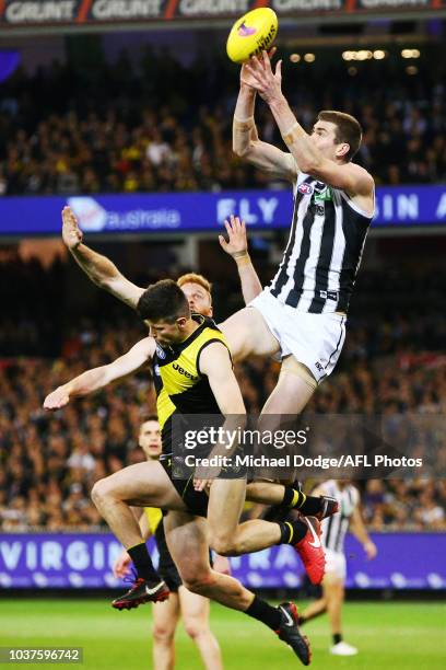 Mason Cox of the Magpies marks the ball over Trent Cotchin of the Tigers during the AFL Preliminary Final match between the Richmond Tigers and the...