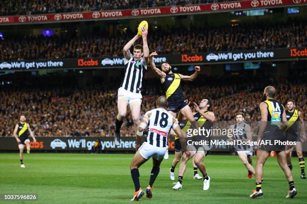 Mason Cox of the Magpies marks the ball against Shane Edwards and Alex Rance of the Tigers during the AFL Preliminary Final match between the...