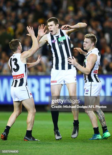 Mason Cox of the Magpies celebrates a goal with Taylor Adams and Jordan de Goey of the Magpies during the AFL Preliminary Final match between the...