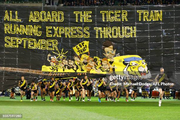 Jack Riewoldt of the Tigers breaks through the banner ahead of teamates during the AFL Preliminary Final match between the Richmond Tigers and the...
