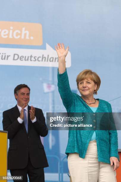 German chancellor Angela Merkel waves onstage at an election campaign event in East Frisian fisher village Neuharlingersiel, Germany, 19 July 2013....