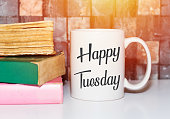 Happy tuesday word on white morning coffee cup and books