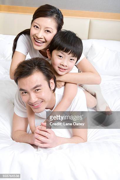 portrait of a young family on a bed - confort at hotel bedroom stock pictures, royalty-free photos & images