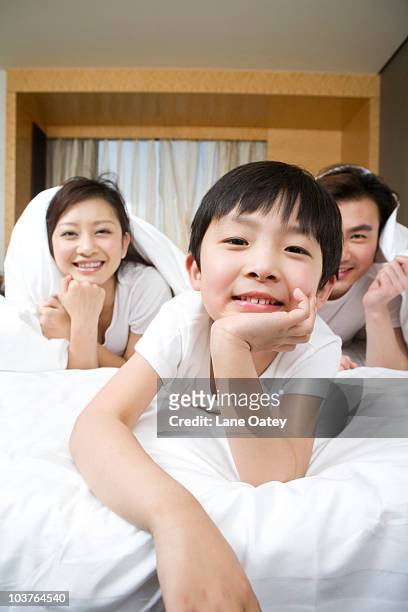 portrait of a young family on a bed - confort at hotel bedroom ストックフォトと画像