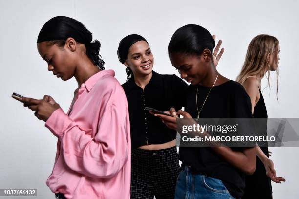 Models check their mobile phone as they wait in the backstage before the Philosophy di Lorenzo Serafini fashion show, as part of the Women's...