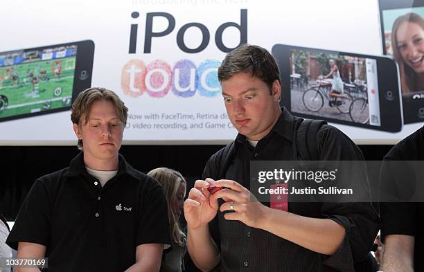 An Apple employee looks on as a member of the media inspects a new iPod Nano at an Apple Special Event at the Yerba Buena Center for the Arts...