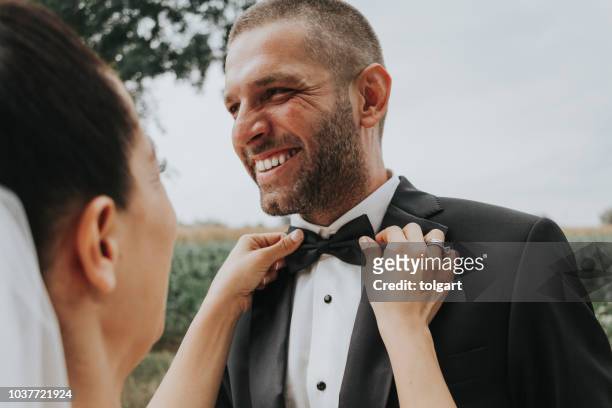 tot vaststelling van de bruidegom bowtie op een bruiloft - get your groom on stockfoto's en -beelden