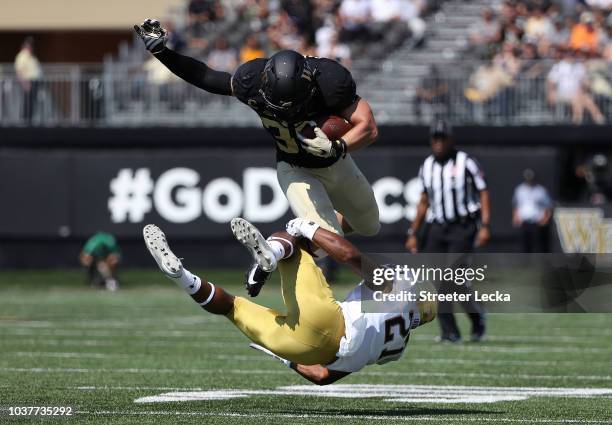 Cade Carney of the Wake Forest Demon Deacons jumps over Julian Love of the Notre Dame Fighting Irish during their game at BB&T Field on September 22,...