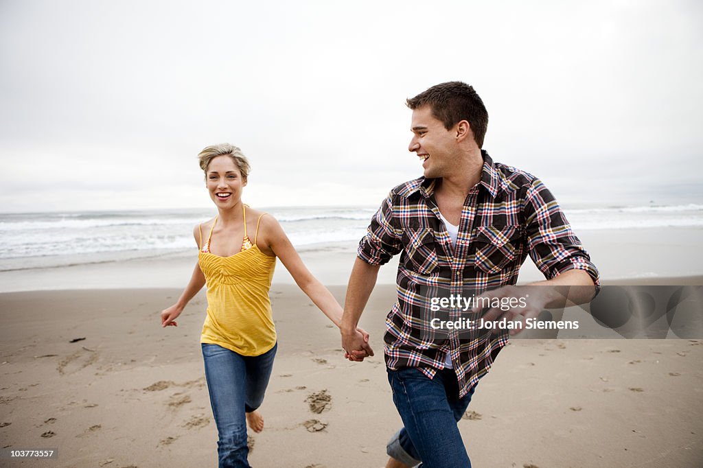 Couple running away from the ocean.