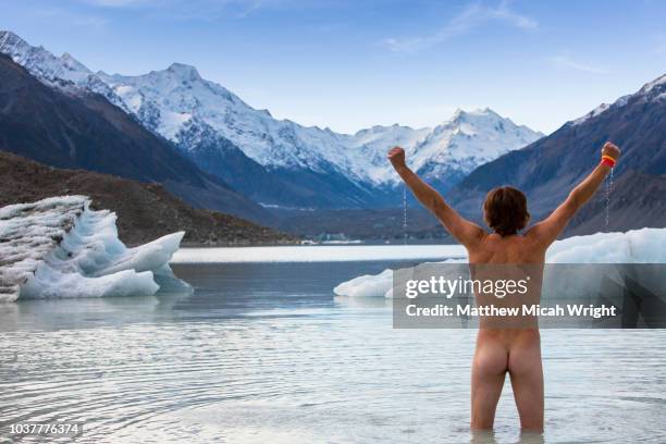 a man walks naked into the icy waters of the glacial lakes of mount cook national park. - bare bum 個照片及圖片檔