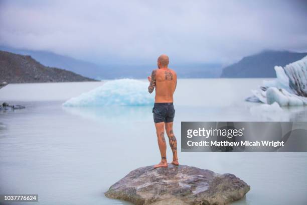 a man swims in the icy glacial waters of mount cook national park. - frozen lake stock pictures, royalty-free photos & images