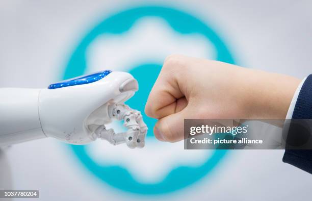 Humanoid robot, "NAO" and a human "fist bump" at the stand of the city library Cologne at the IT fair CeBIT in Hanover, Germany, 21 March 2017. The...