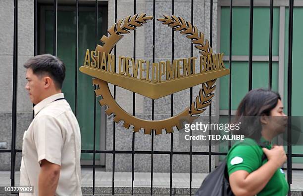 Pedestrians walk past a logo of the Asian Development Bank displayed outside its headquarters in Manila on September 2, 2010. The Philippines said it...
