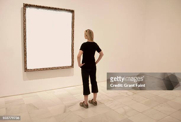 young lady looking at blank art frame. - rückansicht stock-fotos und bilder