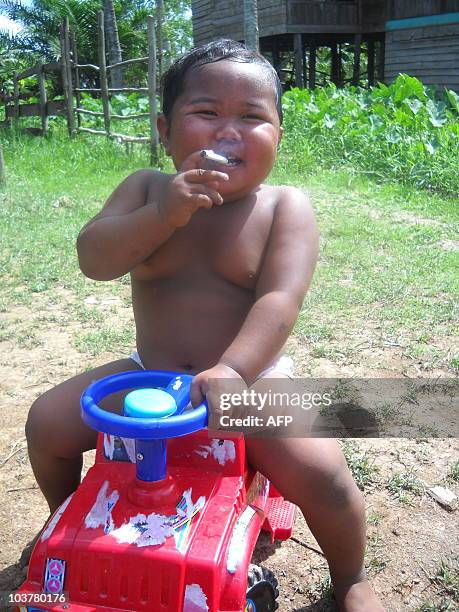 In this photograph taken on May 16, 2010 two-year-old Indonesian boy Ardi Rizal puffs on a cigarette while playing on a plastic toy jeep in the yard...