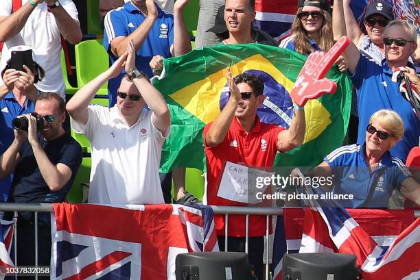 Dean Golding, fiance of gold medalist equestrian athlete Charlotte Dujardin of Great Britain, wears a sign on his shirt, "Can We Get Married Now?"...