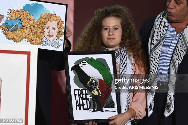 Palestinian activist and campaigner Ahed Tamimi displays a received painting while she attends the Greek Communist Party Youth festival in Athens on...