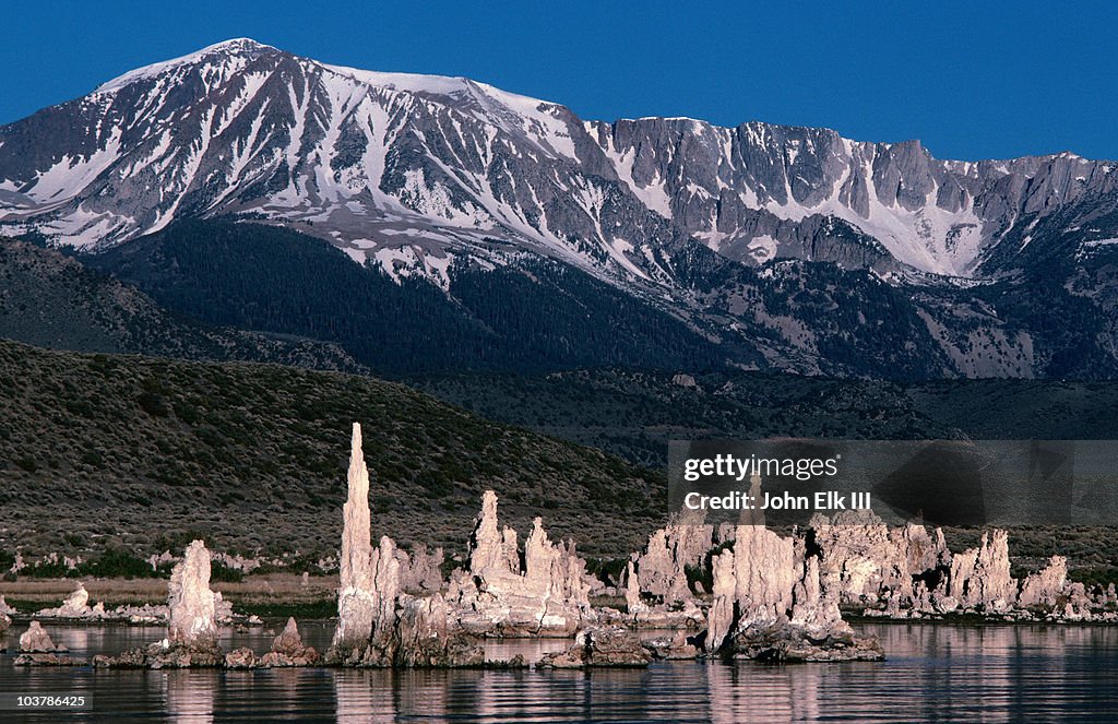 Sand tufa formations in Mono Lake, with backdrop of snow mountains, at sunrise.