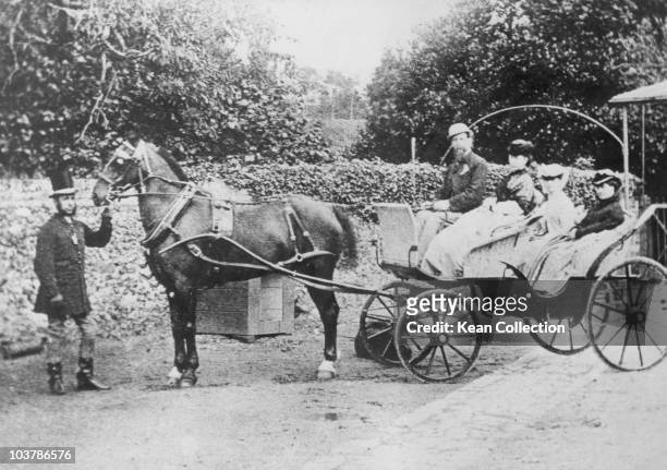 Author Charles Dickens pictured with his wife, Catherine Dickens , and two of their daughters, seated in a horsedrawn carriage, circa 1850. A man...