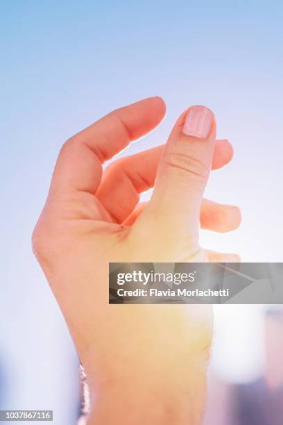 woman's hand against sunny blue sky - snaps her fingers stock pictures, royalty-free photos & images