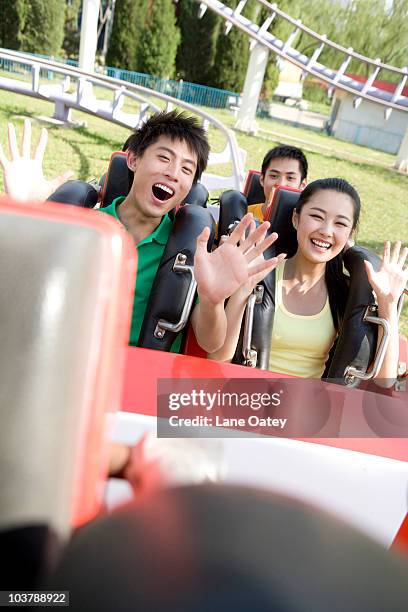 young people riding a rollercoaster - young woman screaming on a rollercoaster stock-fotos und bilder