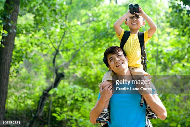 father and son in the great outdoors - asian child with binoculars stockfoto's en -beelden
