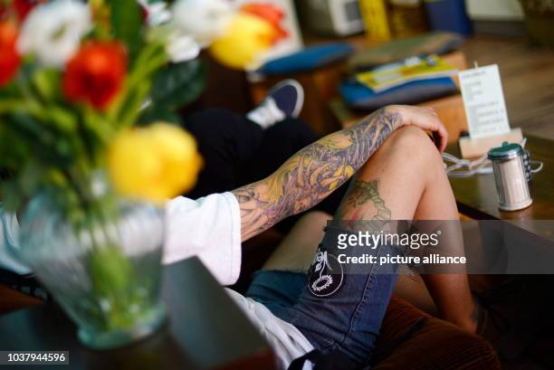 Tattoed sits in the vegan cafe "Edelkiosk" in Frankfurt Main, Germany, 17 July 2013. Anna Prokein is opening the first vegan cafe in Frankfurt....